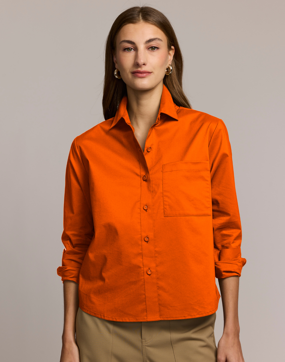 Woman wearing an orange shirt against a plain background