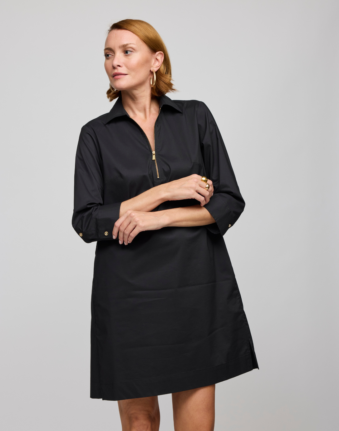 A woman wearing a black, 3/4 sleeve Alessa dress with a collar, made from stretch polished cotton.