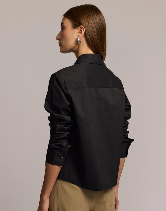 Woman wearing a black shirt against a beige background