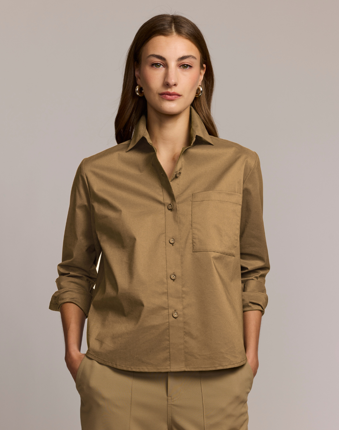 Woman wearing a brown shirt with a plain background