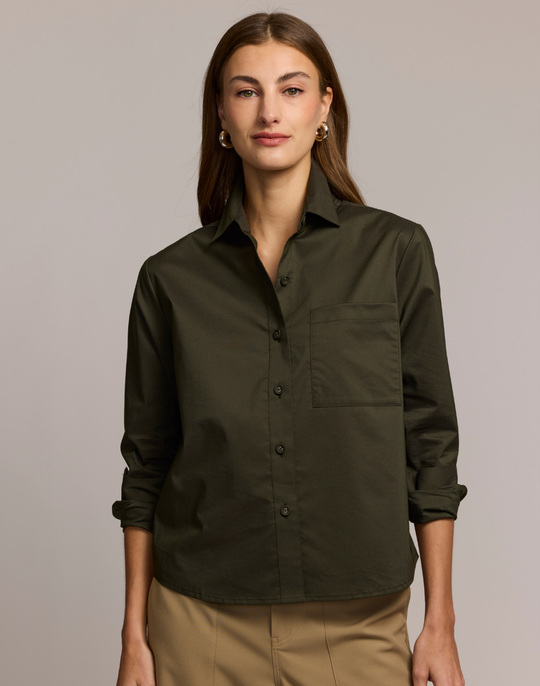 Woman wearing an olive green button-up shirt against a plain background