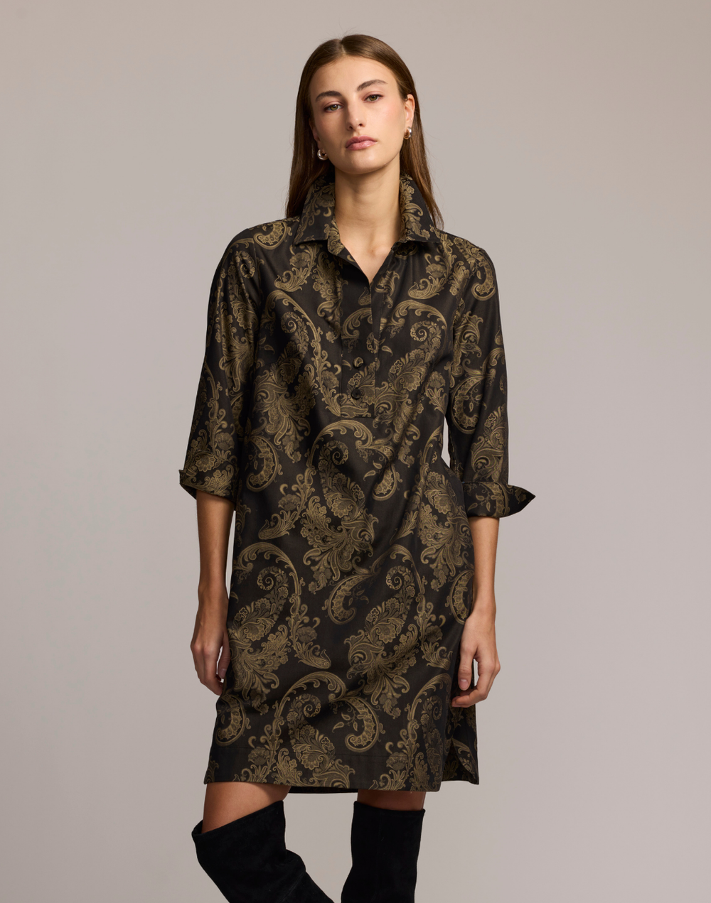 Woman wearing a beige and black patterned dress against a plain background